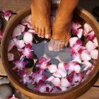 Woman&#039;s Feet In Basin Of Orchid Flower Water