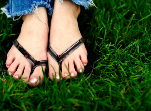 Feet Wearing Flip Flops in the Grass
