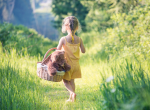 Barefoot Girl Walking In Field With Basket and Teddy Bear
