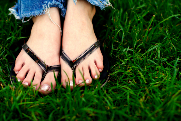 Feet Wearing Flip Flops in the Grass