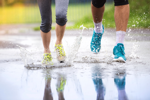 Couple Jogging Through Puddles In Bright Athletic Shoes