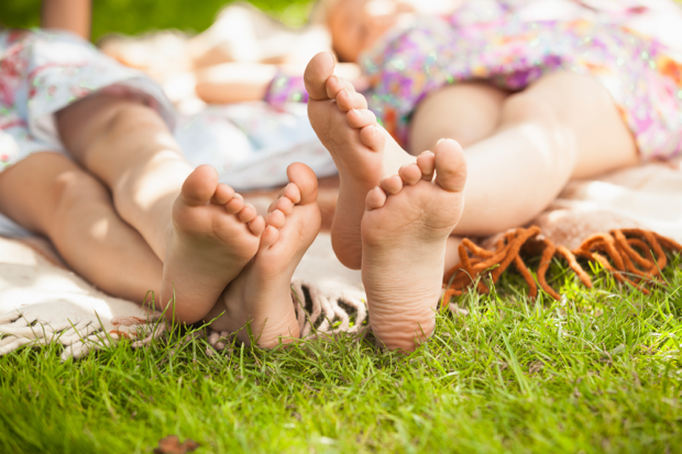 Girls Laying In the Park Barefoot On A Blanket